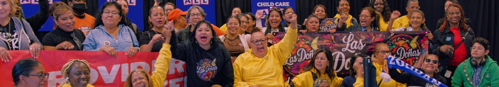 POP and Las Doñas members cheering behind their banners